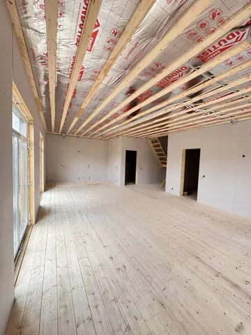 Гостиная двухэтажного дома 140 м² до отделки: балки перекрытия и лестница