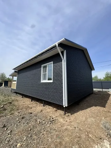 Каркасный дом 80 м² с тёмным фасадом под кирпич, вид с угла